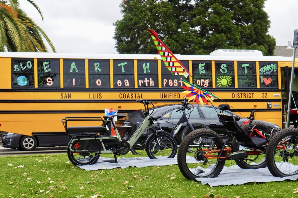 SLO EarthFest volunteers with bikes and a decorated bus for climate awareness.